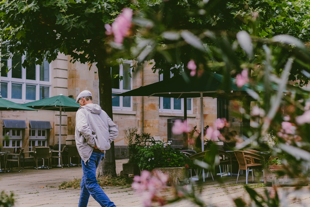 Man walking past outdoor cafe with pink flowers